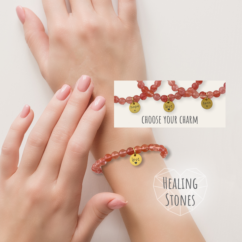 Two hands wearing red beaded bracelets with charms on a light background