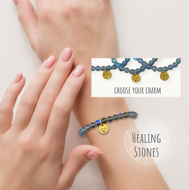 Two hands wearing a blue beaded bracelet with gold charms on a light background.